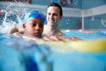 Child at swimming lessons with swim coach